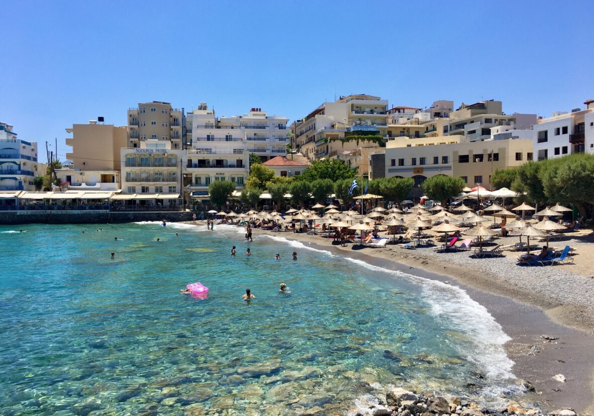 Helder zeewater, zwemmers en parasols op het stadsstrand Kitroplatia