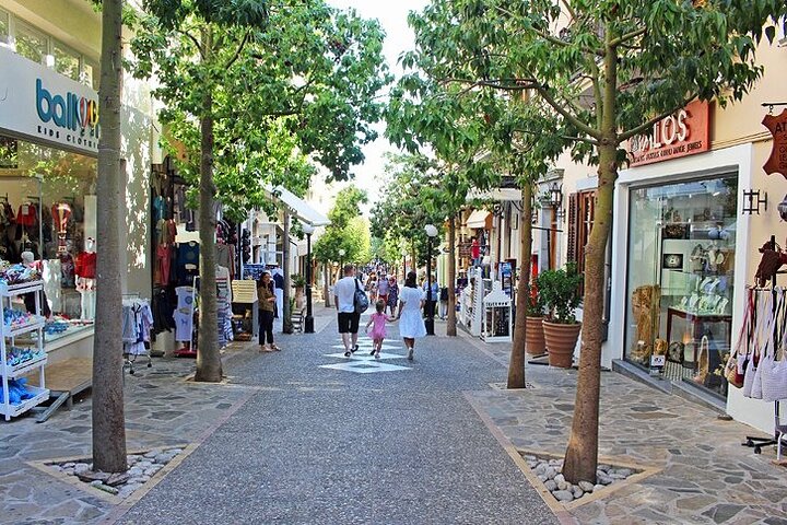 Een winkelstraat met bomen, kleine winkels en wandelende bezoekers